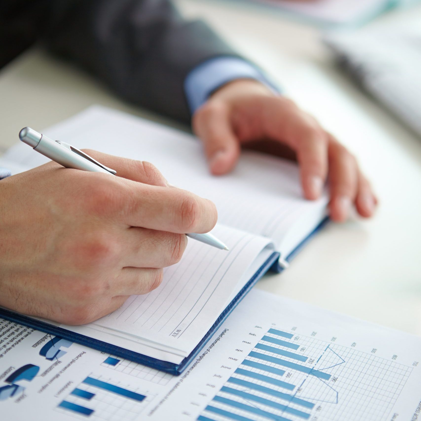 Businessman hand with pen over open notebook making report